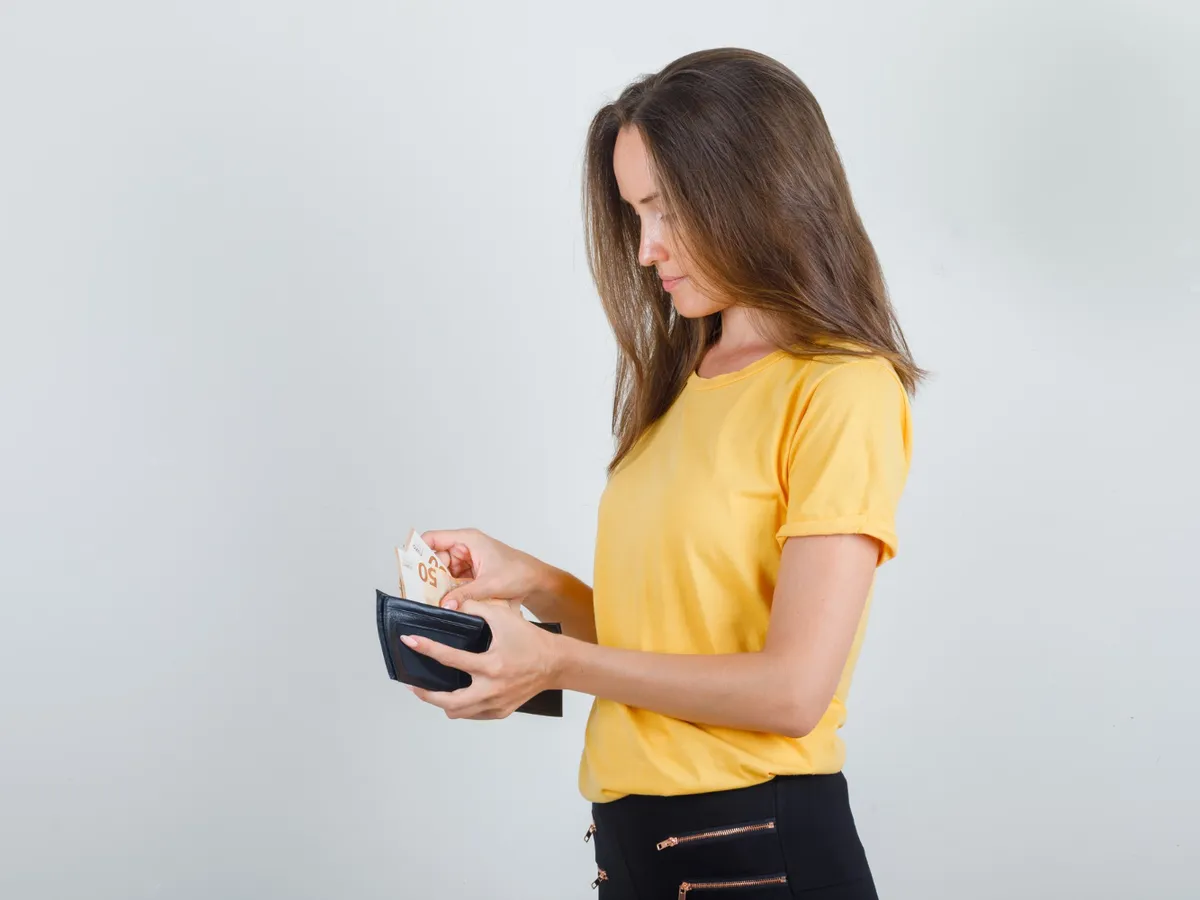 Femeie care pune banii în portofel - Foto: Freepik (Imagine cu rol ilustrativ)