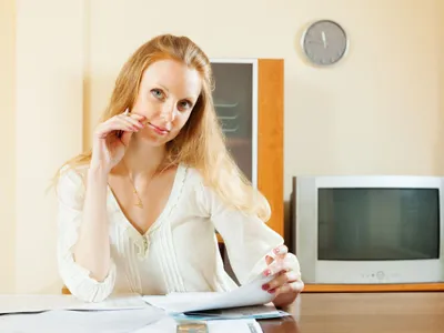 Femeie blondă uitându-se peste documente financiare - Foto: Freepik/bearfotos