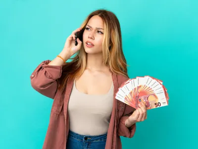 Femeie cu euro în mână care vorbește la telefon - Foto: Magnific.com (Imagine cu rol ilustrativ)