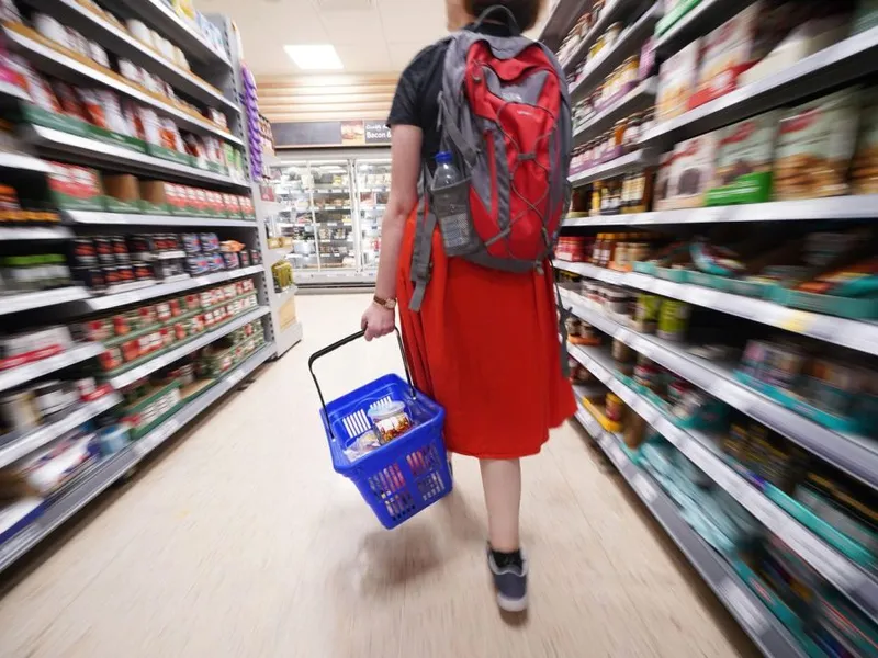 Cumpărător mergând printre două insule de produse comercializate, în hypermarket - Foto: Profimedia Images
