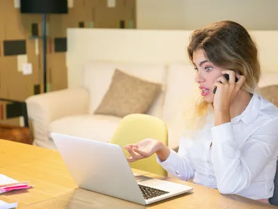 O femeie vorbește la telefon în fața laptopului - Foto: Magnific.rom (rol ilustrativ)