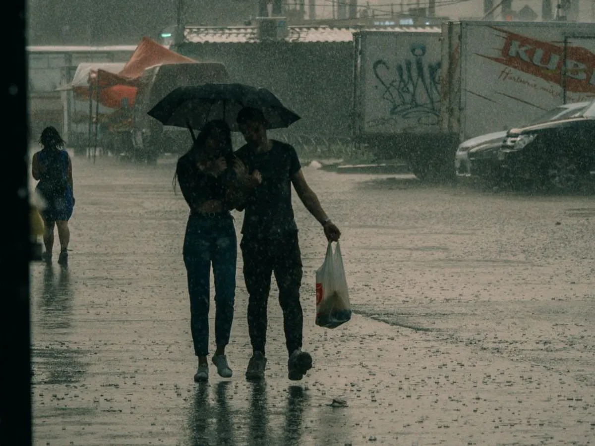 Tânăr cuplu mergând prin ploaie, sub umbrelă - Foto: Pexels/Nikita Korchagin