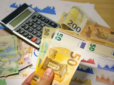 Bancnote de euro şi lei, cu un calculator pe birou - Foto: Pexels/Jakub Zerdzicki