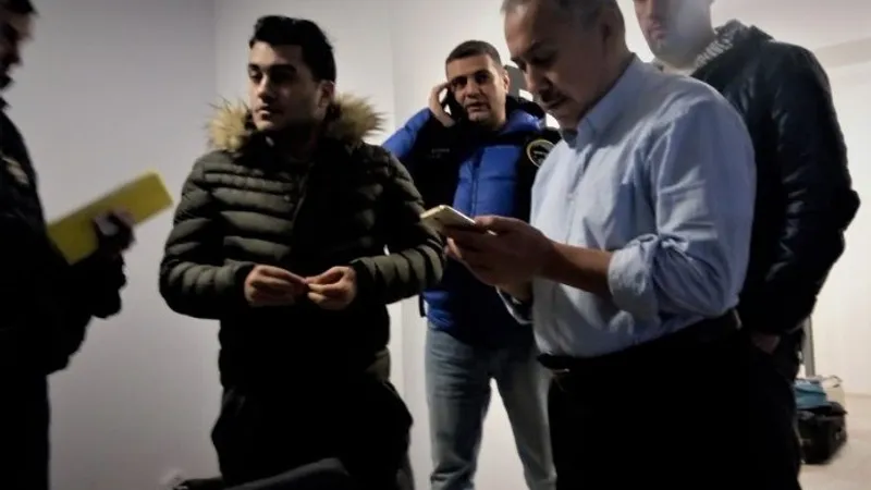 Kamil Demirkaya, în stânga imaginii, cu un telefon în mână Foto: zaman România