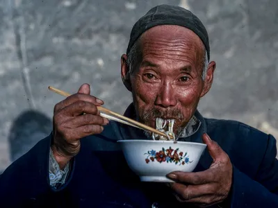 Chinez în vârstă mâncând cu ajutorul bețișoarelor - Foto: Profimedia