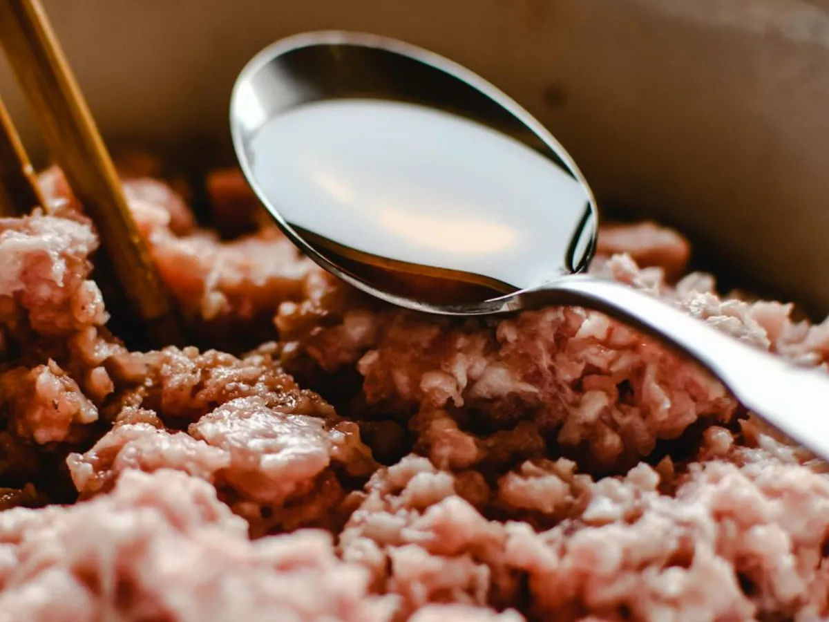 Lingură din oţel inoxidabil cu ulei în ea, deasupra cărnii tocate de porc - Foto: Pexels-Eva Bronzini