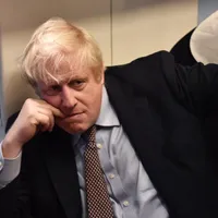Boris Johnson se agață cu dinții de scaun/ FOTO: The Guardian