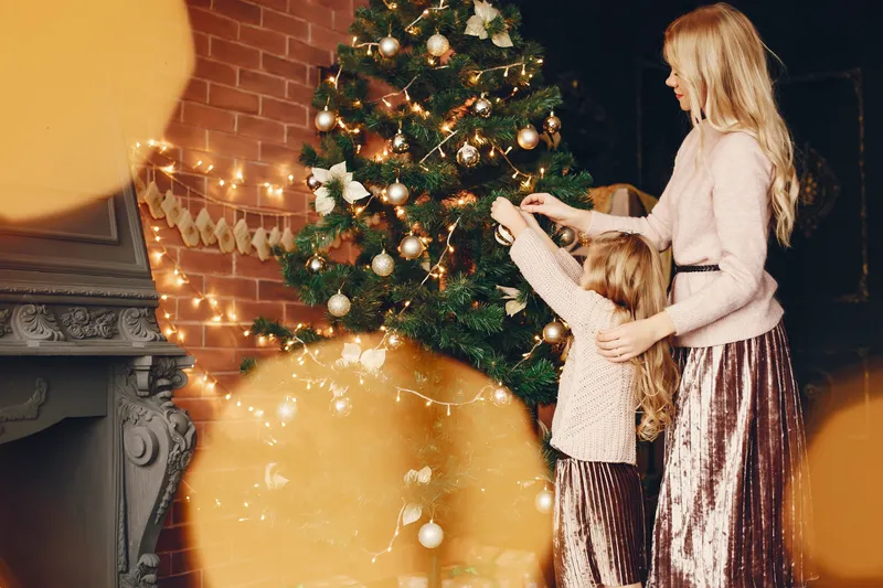 Familie care pune &icirc;n brad globuri - Foto: Freepik (Imagine cu rol ilustrativ)