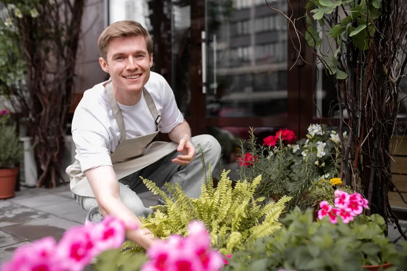 Bărbat care &icirc;ngrijește florile de la bloc - Foto: Magnific.com (Imagine cu rol ilustrativ)