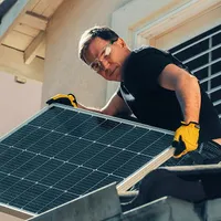 Bărbat montând un panou solar pe casă - Foto: Pexels/Kindel Media