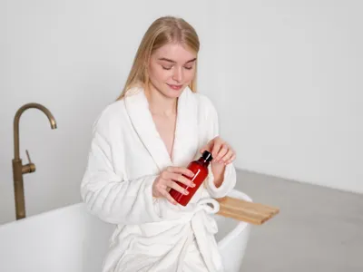 Femeie în halat care ține un șampon în mână - Foto: Freepik (imagine cu rol ilustrativ)