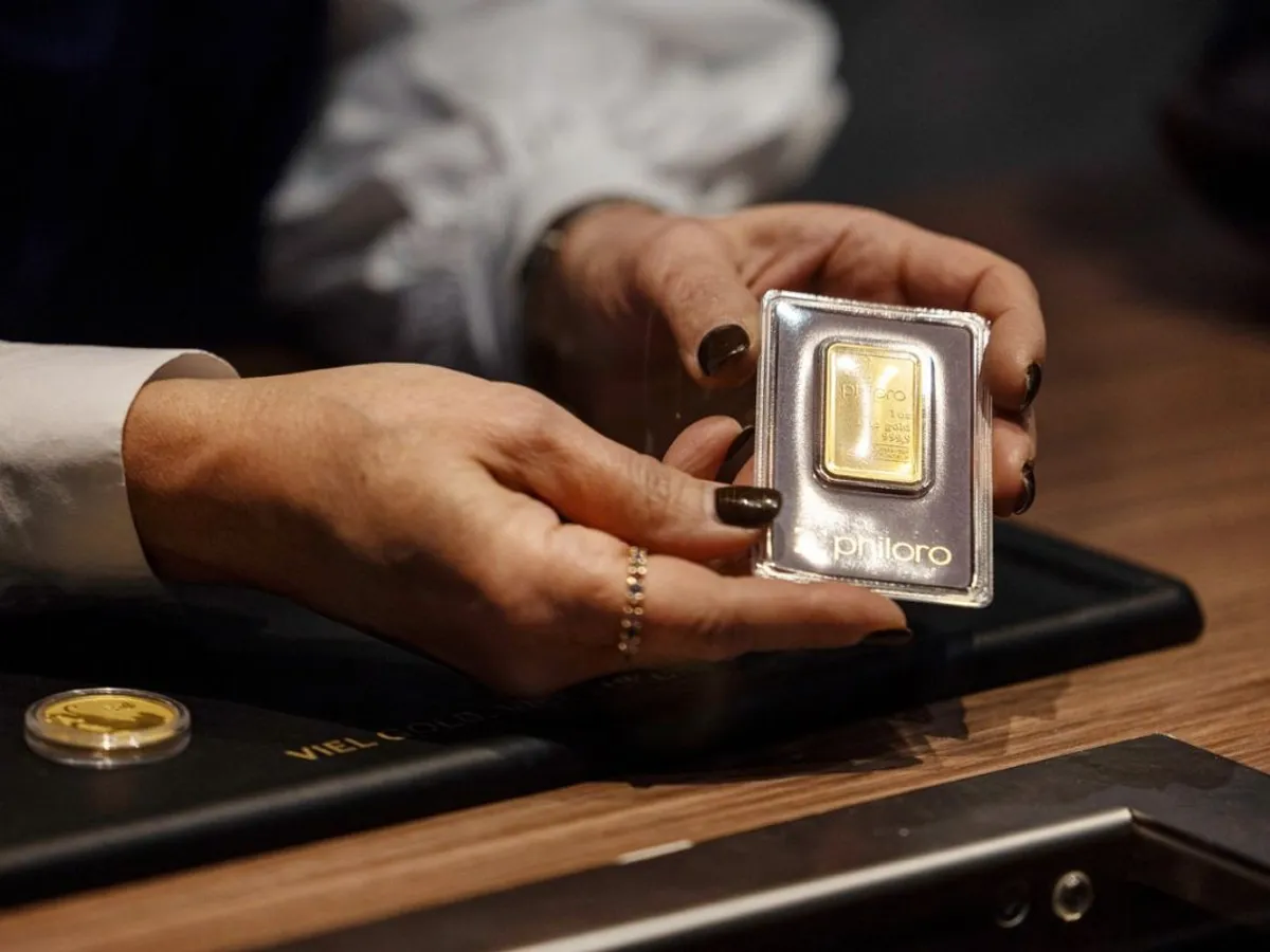 O comerciantă de metale prețioase ține în mână o placă de aur - Foto: Profimedia Images
