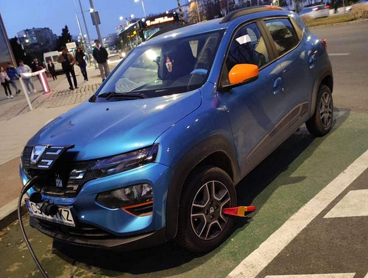 Mașină electrică pusă la încărcat la o stație publică, cu roata blocată de primărie. - Foto: Facebook/Valentin Burghiu