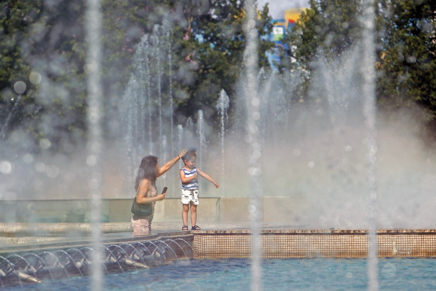 Femeie cu copil pe marginea unei fântâni, în Bucureşti - Foto: Profimedia Images